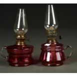 TWO LATE VICTORIAN/EDWARDIAN CRANBERRY GLASS OIL LAMPS, THE RESERVOIRS WITH CLEAR LOOP HANDLES,