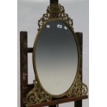 A VICTORIAN OVAL ENGRAVED BRASS DRESSING MIRROR, THE UNBEVELLED PLATE IN GUILLOCHE BORDER, LEAFY