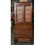 AN OAK BUREAU BOOKCASE, THE UPPER SECTION WITH LEADED DOOR, CONVENTIONAL INTERIOR ABOVE TWO LONG