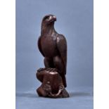 A JAPANESE CARVED AND STAINED WOOD SCULPTURE OF A HAWK, 19TH/20TH C, PERCHED ON A ROCK WITH