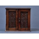 AN OAK SMOKER'S CABINET, EARLY 20TH C, ENCLOSED BY A PAIR OF ROSETTE AND LEAF SCROLL CARVED DOORS,