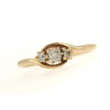 A THREE STONE DIAMOND CROSSOVER RING, WITH CUSHION SHAPED AND ROUND OLD CUT DIAMONDS, IN GOLD MARKED