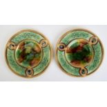 A PAIR OF MAJOLICA PLATES, C1880, WITH MOULDED BORDER PANELS OF ENTWINED FOLIAGE, THE CENTRE IN