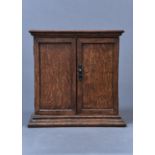 AN OAK SMOKER'S CABINET, C1920, ENCLOSED BY A PAIR OF PANELLED DOORS, THE INTERIOR WITH OPEN