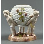 A PLAUE FLORAL ENCRUSTED BASKET SHAPED VASE, LATE 19TH C, SUPPORTED BY THREE PUTTI STANDING ON ROUND