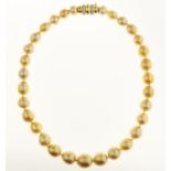 A GOLDEN SOUTH SEA CULTURED PEARL NECKLACE, THE SINGLE STRAND OF THIRTY ONE OVAL AND DROP SHAPED