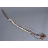 TRIBAL ART. A WOOD, LEATHER AND FIBRE ARCHER'S BOW APPLIED WITH THREE STRINGS OF COWRIE SHELLS,
