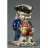 A BRITISH EARTHENWARE HUNCH BACK JUG-AND-GLASS TOBY JUG, PROBABLY SCOTTISH, C1900, WITH DEFINED