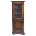 A REPRODUCTION OAK STANDING CORNER CUPBOARD, C1960, FLARED CORNICE ABOVE A GLAZED DOOR APPLIED