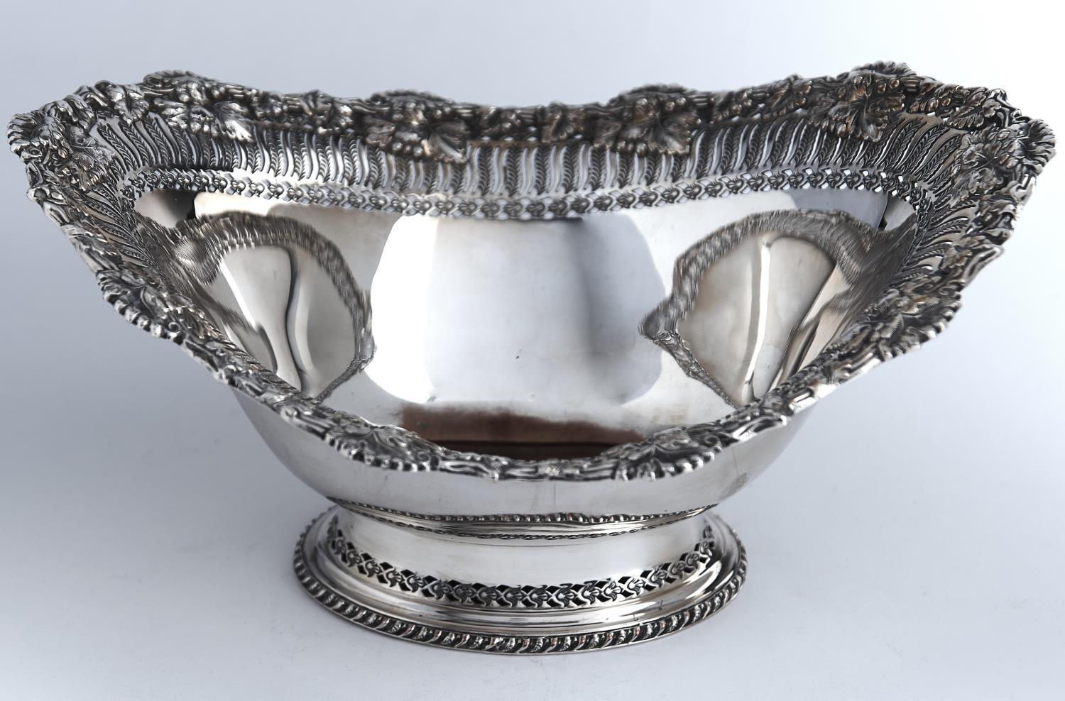 AN OVAL EPNS FRUIT BOWL, EARLY 20TH C, WITH LEAF-PIERCED BORDER AND APPLIED FOLIATE RIM, ON