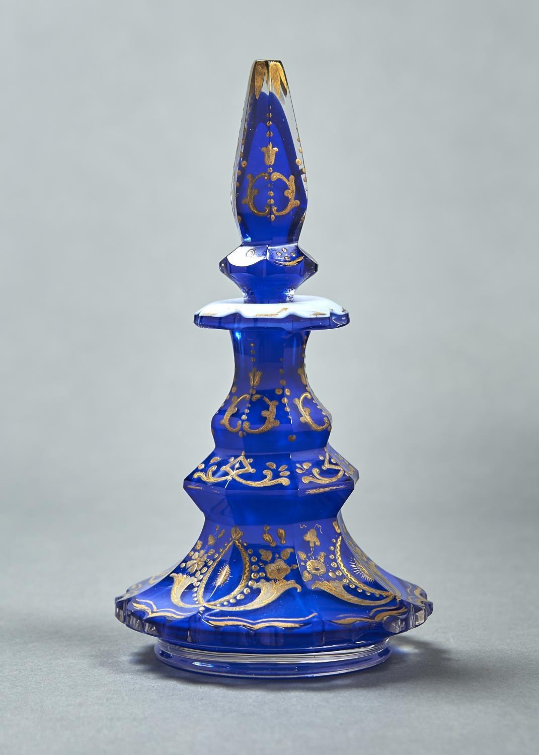 A CASED GLASS SCENT BOTTLE AND STOPPER, C1860, OF OPAL CASED IN BLUE GLASS WITH RAISED GILDING, 16.