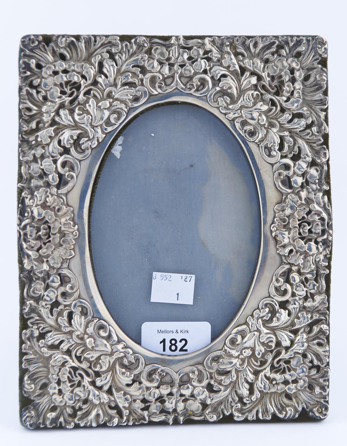 AN EDWARDIAN SILVER PHOTOGRAPH FRAME, THE OVAL APERTURE TO THE DIE STAMPED MOUNT SURROUNDED BY A