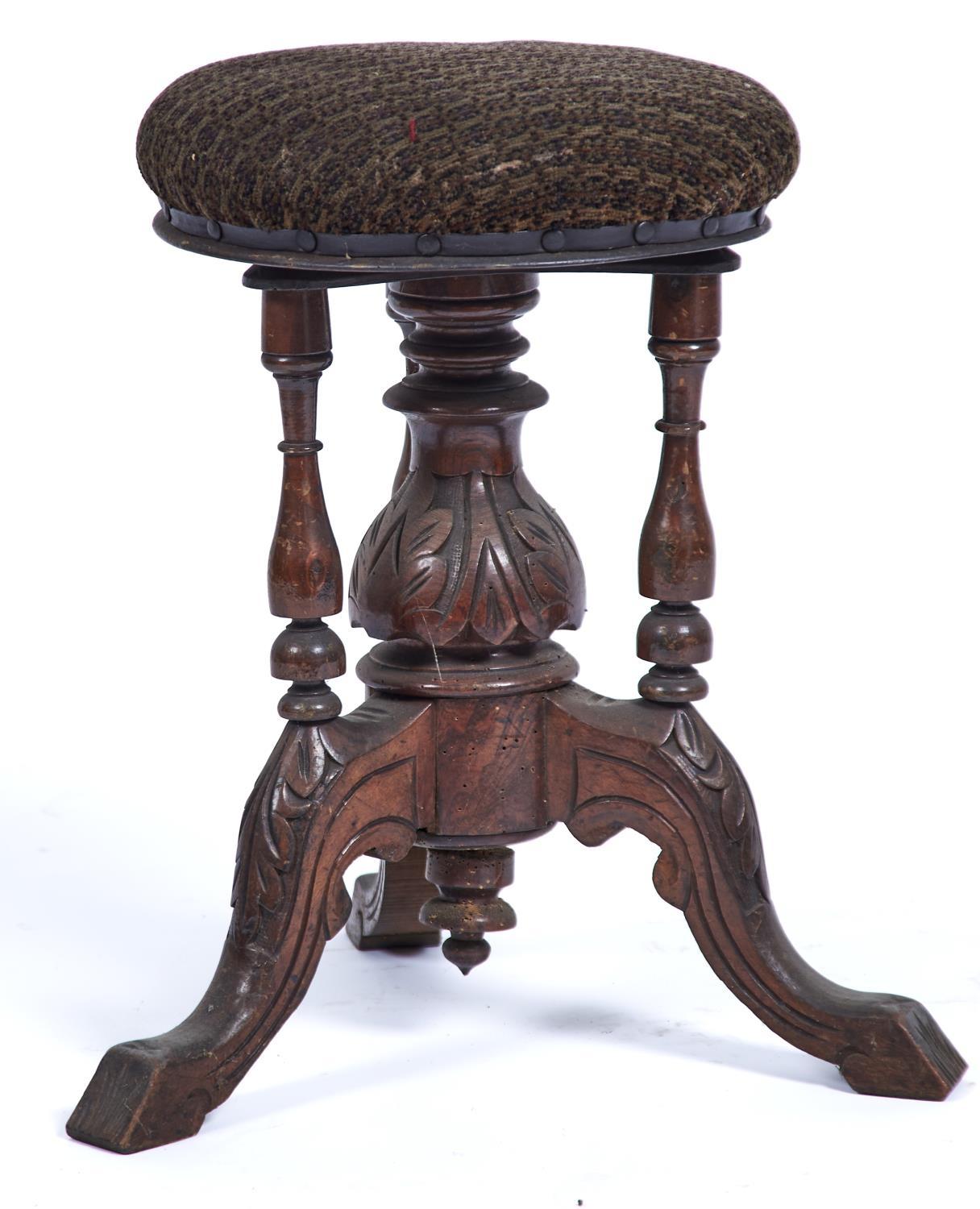 A VICTORIAN WALNUT PIANO STOOL, THE CIRCULAR STUFFED OVER TOP ABOVE FOLIATE CARVED CENTRE COLUMN AND