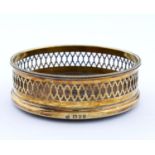 AN ELIZABETH II SILVER GILT WINE COASTER, PIERCED BENEATH REEDED RIM, INSET TURNED MAHOGANY BASE,