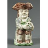 A STAFFORDSHIRE CREAMWARE TOBY JUG, C1780, DECORATED IN PREDOMINANTLY GREEN AND MANGANESE, THE