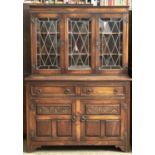 AN OAK DRESSER, MOULDING ABOVE THREE LEAD GLAZED DOORS WITH SHELVED INTERIOR, THE PROJECTING BASE