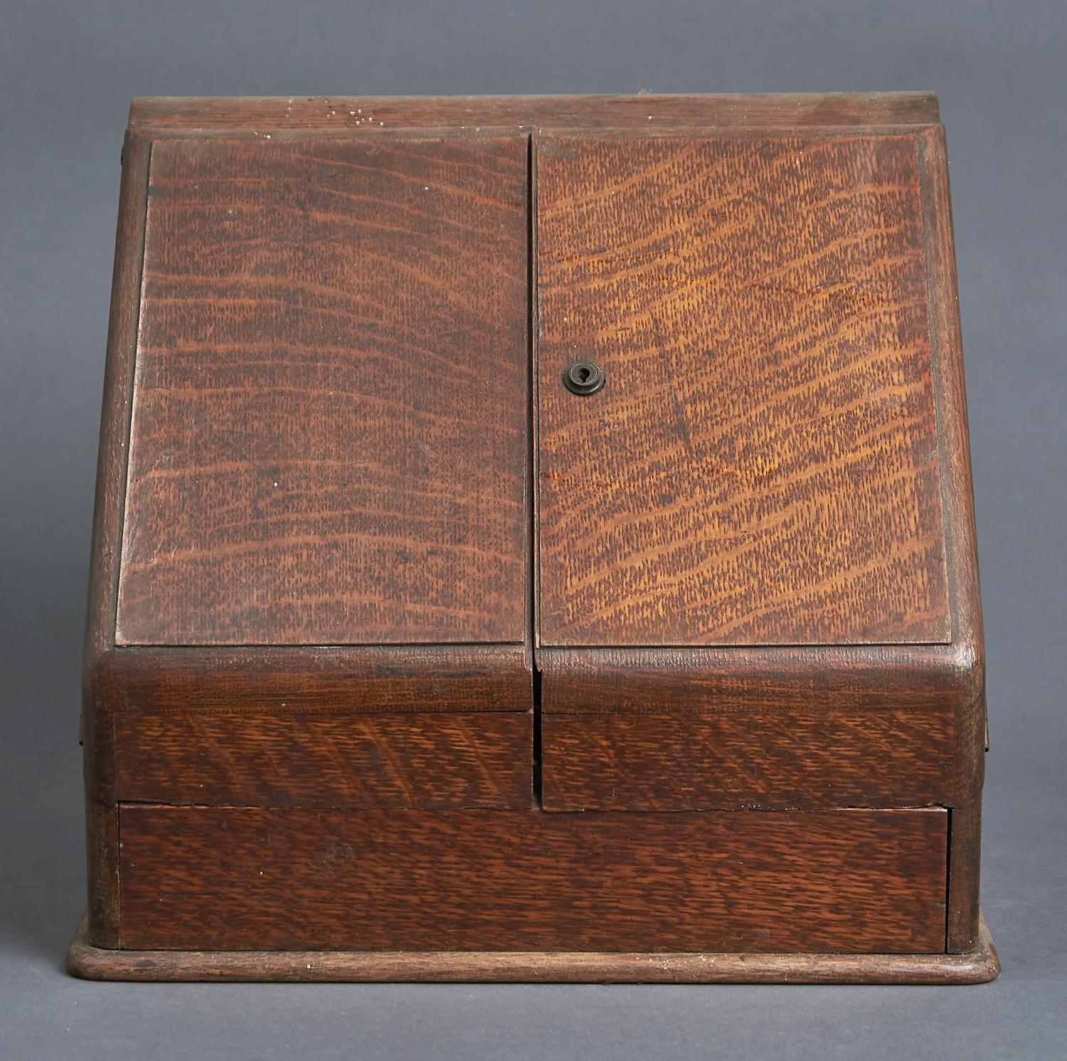 A VICTORIAN OAK SLOPE FRONT STATIONERY BOX, THE HINGED OGEE TOP AND PAIR OF DOORS OPENING TO