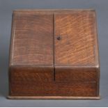 A VICTORIAN OAK SLOPE FRONT STATIONERY BOX, THE HINGED OGEE TOP AND PAIR OF DOORS OPENING TO