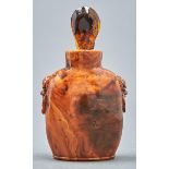 A Chinese amber snuff bottle, 20th c, carved with mask and ring handles, 75mm h, amber tear shaped