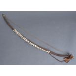 Tribal art. A wood, leather and fibre archer's bow applied with three strings of cowrie shells,