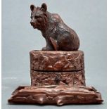 A Swiss carved and stained limewood bear novelty inkwell, c1900, in the form of a bear cub seated on
