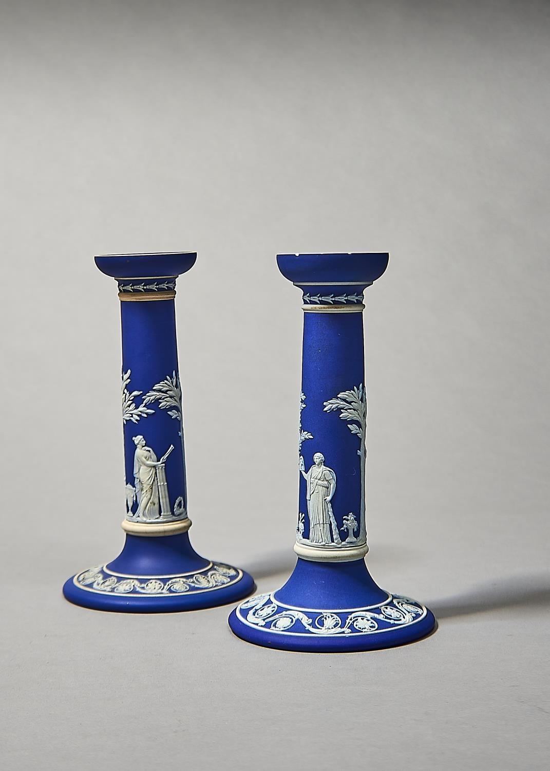 Two similar Wedgwood dark blue jasper dip candlesticks, early 20th c, sprigged with Apollo and