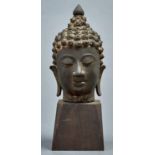 A South East Asian bronze sculpture of the head of Buddha, 20th c, 18.5cm h, wood base Good