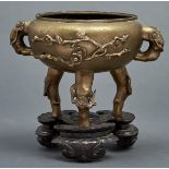 A Chinese bronze tripod censer, 19th c, cast with prunus, 17cm h, commendation mark, wood stand