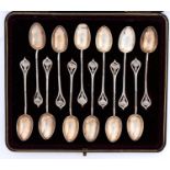 A set of twelve art nouveau silver coffee spoons, with flower terminal and twisted stem, bowls gilt,