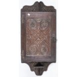 A Victorian carved and dark stained oak hanging corner cupboard, c1900, with iron serpent hinges,