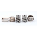 A pair of Edwardian EPNS seated fox napkin rings, another, a rectangular silver napkin ring and an