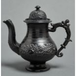 A Staffordshire black glazed earthenware teapot and cover, c1870, with scrolling handle and sprigged