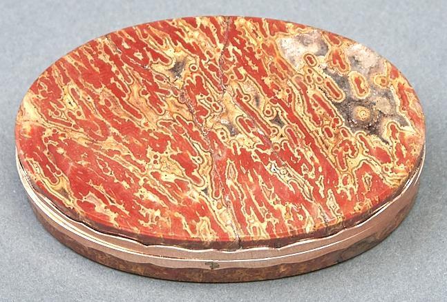 An oval giltmetal mounted hardstone snuff box, early 19th c, with wavy edged mount, 76mm l Lid