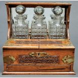 A Victorian oak tantalus, with silver plated strapwork mounts, the top and hinged base with relief