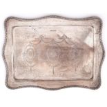 A George V serpentine silver dressing table tray, engraved with festoons and paterae, 29cm l, by