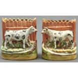 A pair of Staffordshire flatback spill holders in the form of a cow before a fence, late 19th c,