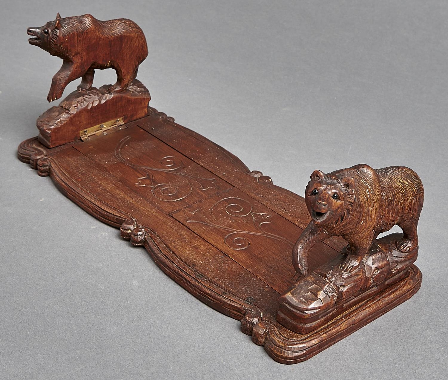 A Swiss carved and stained limewood book slide, the ends in the form of a bear, early 20th c, 34cm l