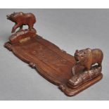 A Swiss carved and stained limewood book slide, the ends in the form of a bear, early 20th c, 34cm l