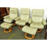 A set of three Stressless cream leather armchairs and a pair of matching stools, armchairs 62cm w