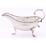 A George III silver sauce boat, with leaf capped flying scroll handle, crimped rim and three hoof