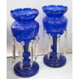 A pair of late Victorian blue glass lustre stands, with cut rims and cylindrical reservoirs on