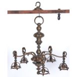 A brass chandelier, c1920, of five lights with mushroom knopped baluster shaft and swan neck