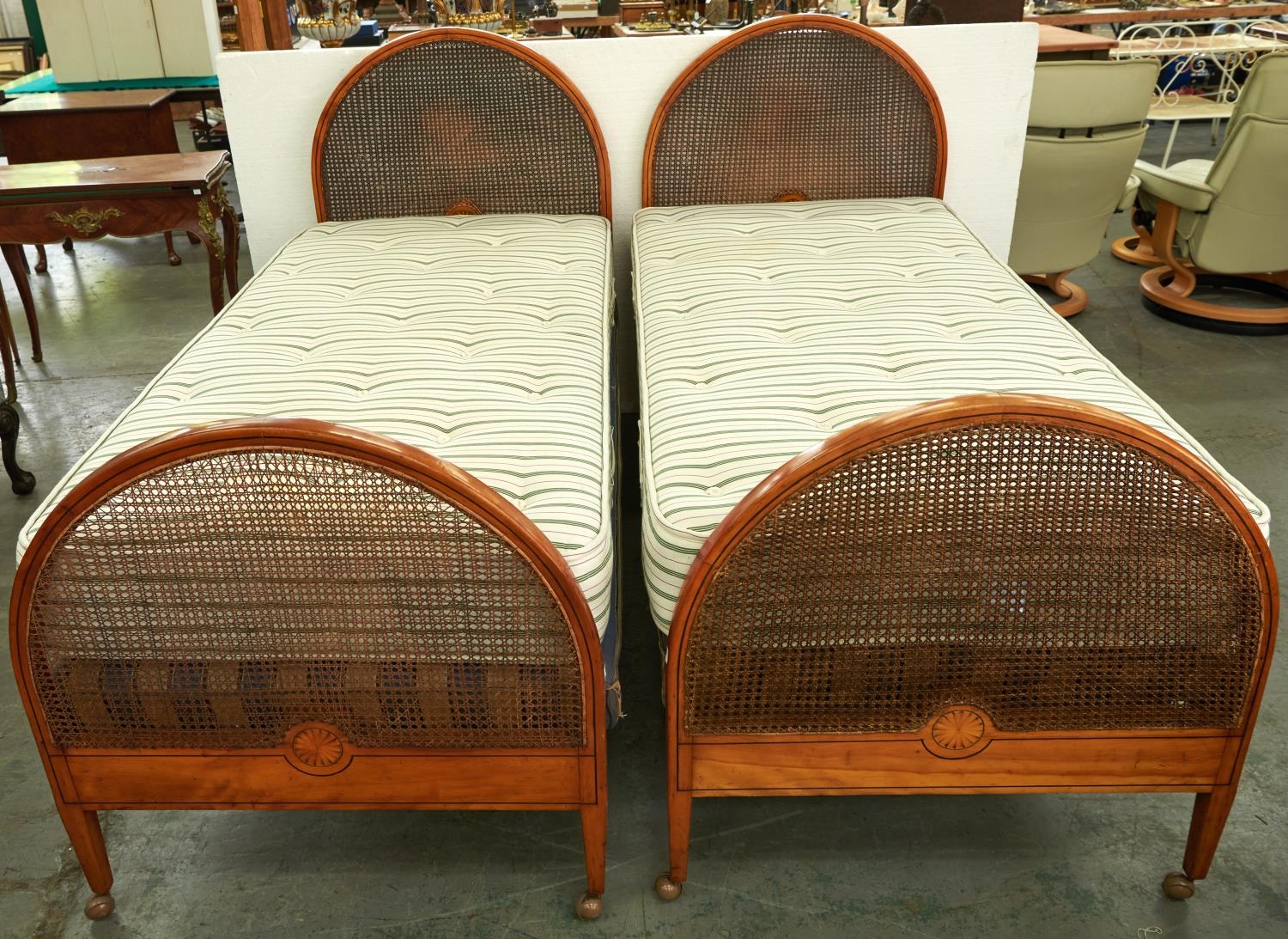 A pair of Edwardian arched and inlaid mahogany and caned single beds, c1910, with bed irons, bases