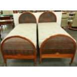 A pair of Edwardian arched and inlaid mahogany and caned single beds, c1910, with bed irons, bases