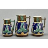 A set of three graduated majolica jugs, c1880, moulded with dolphins on a blue band between