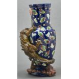 A majolica dragon vase, late 19th c, the scaly olive green creature clinging to the blue vase, the