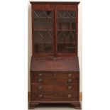 A George III mahogany bureau-bookcase, early 19th c, the bureau with fitted interior, on ogee