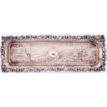An Edwardian die stamped silver comb tray, decorated with flowers, scrolls and spume, 22.5cm l, by