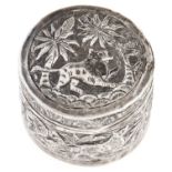 An Indian silver repousse round box and cover, c1900, decorated with tiger, elephants and trees,