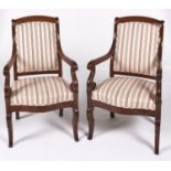 A pair of French mahogany armchairs, 19th c, the over-scrolled arms terminating in lappets, on s-